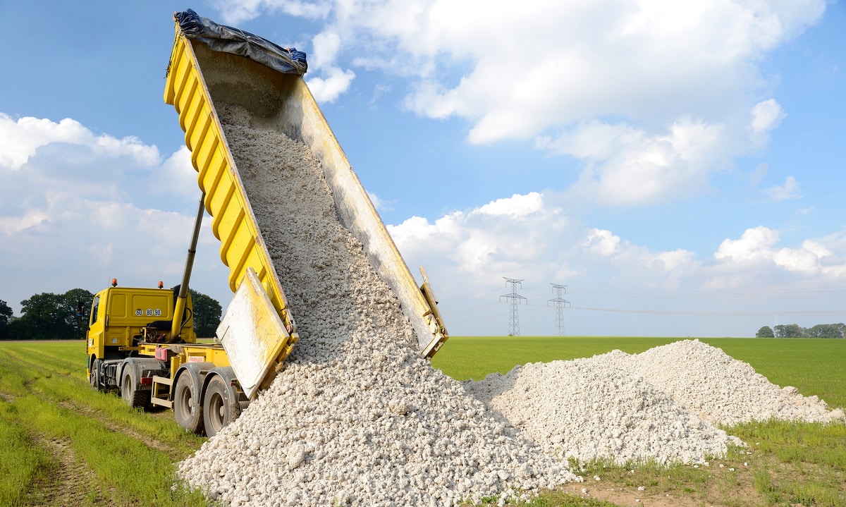 Lastebil som losser kalkstein på landlig eiendom